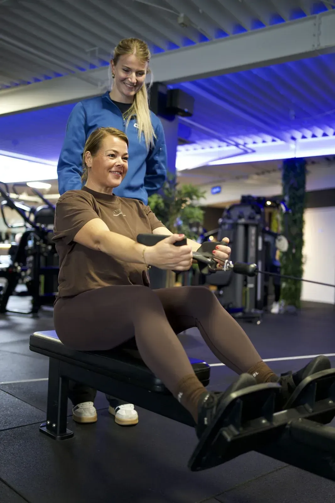 Trainer coacht een lid op een krachttoestel